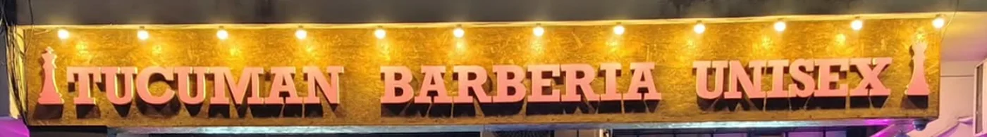 Cartel iluminado que dice Tucumán Barbería Unisex